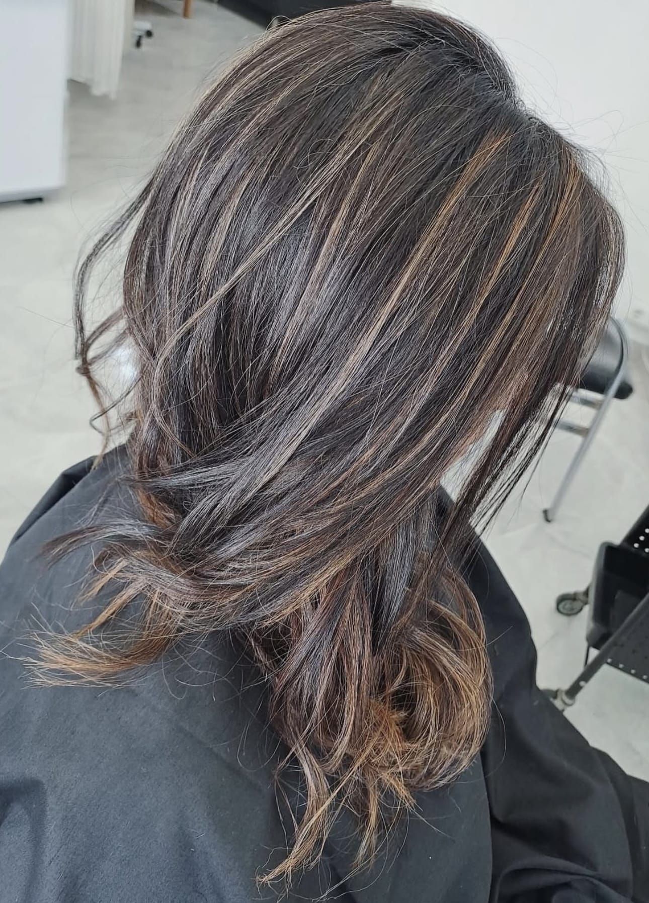 Una mujer está sentada en una silla con el pelo recogido en un moño.