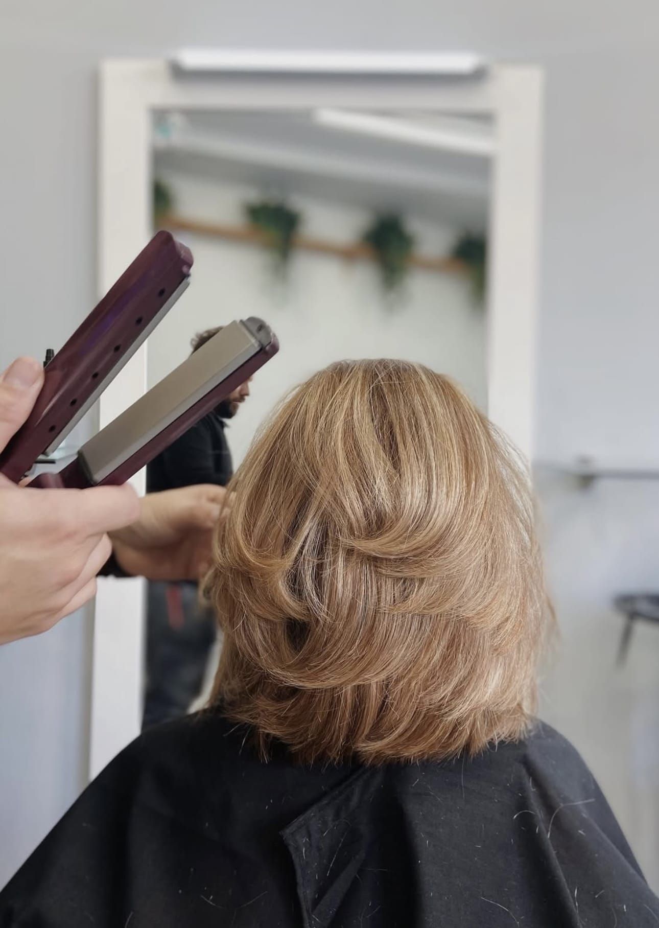 Una mujer se está alisando el cabello en una peluquería.