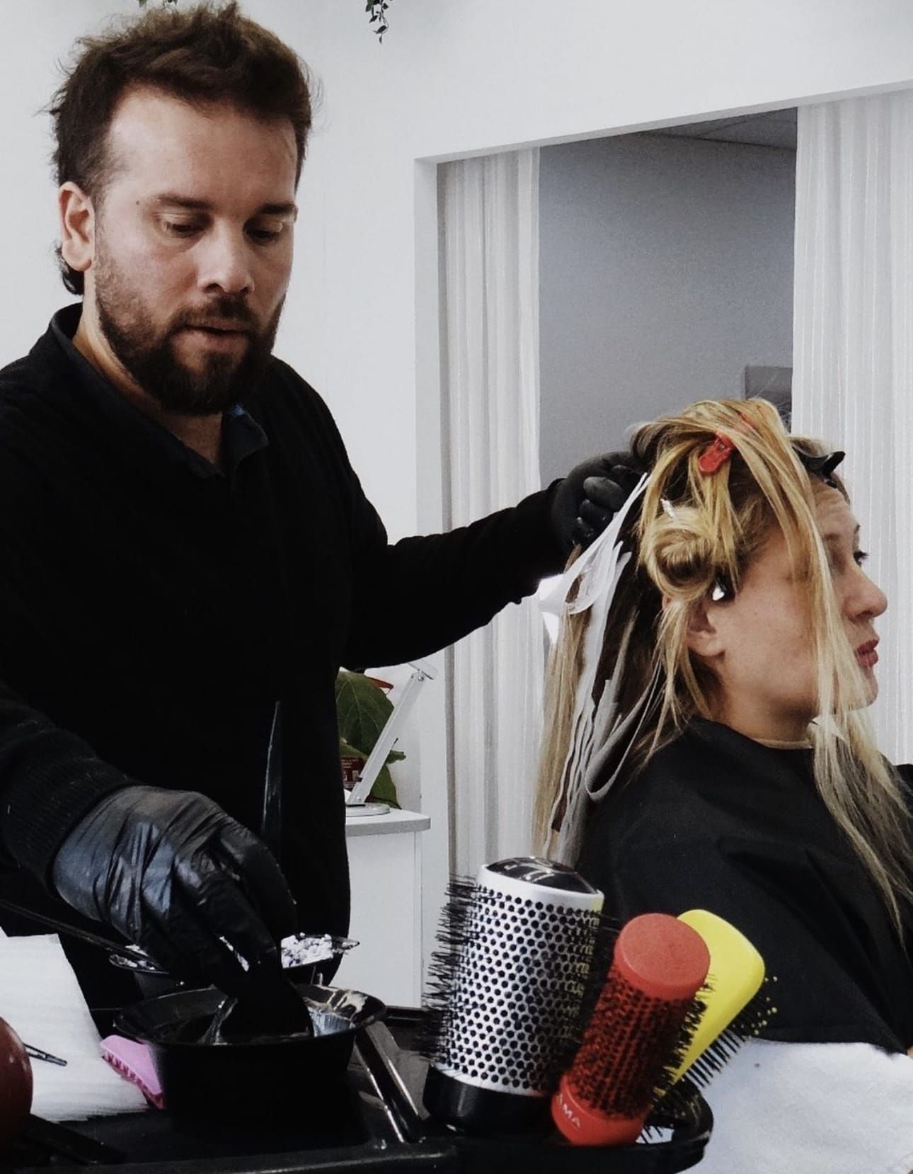Un hombre está cepillando el cabello de una mujer en un salón.