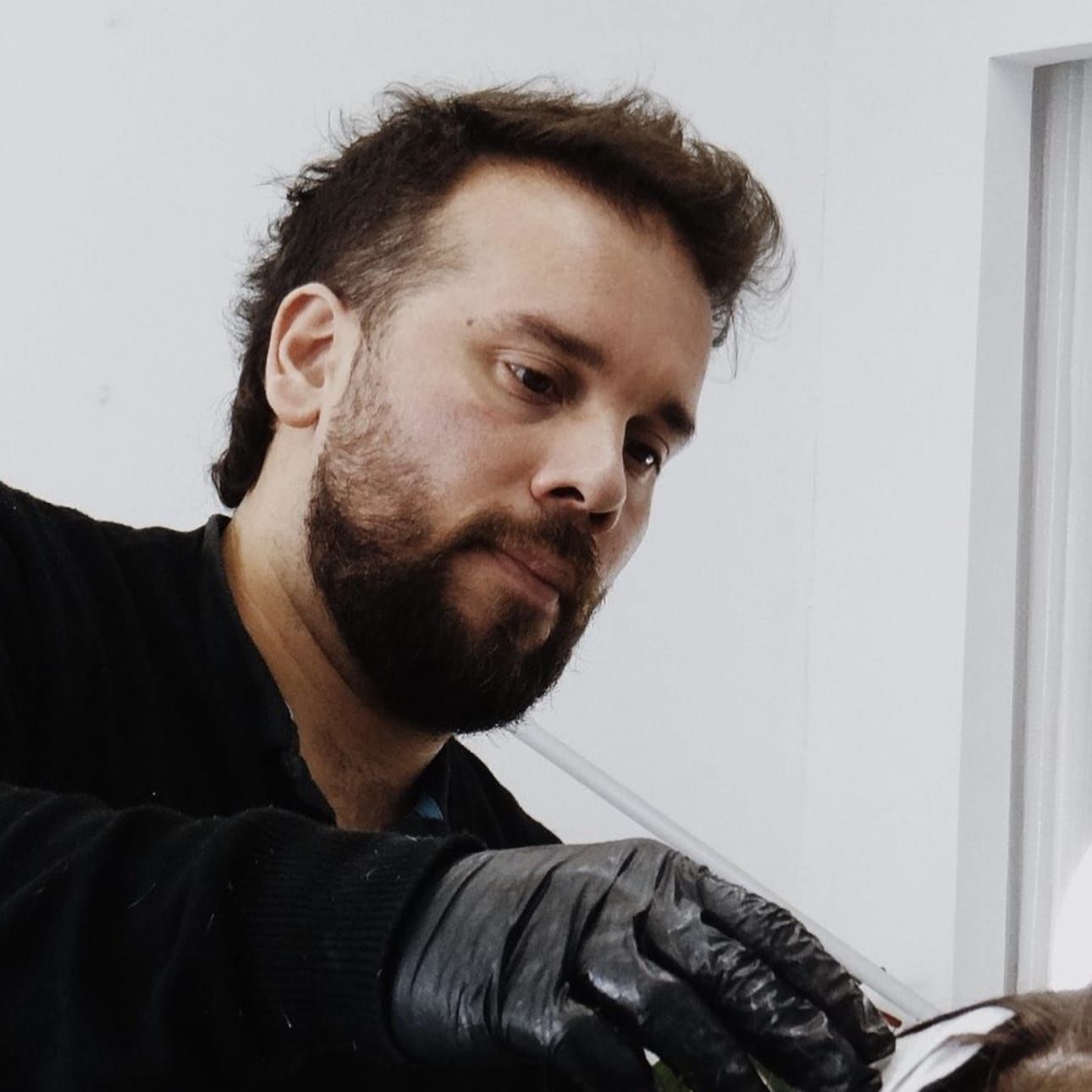 Un hombre con barba lleva guantes negros.
