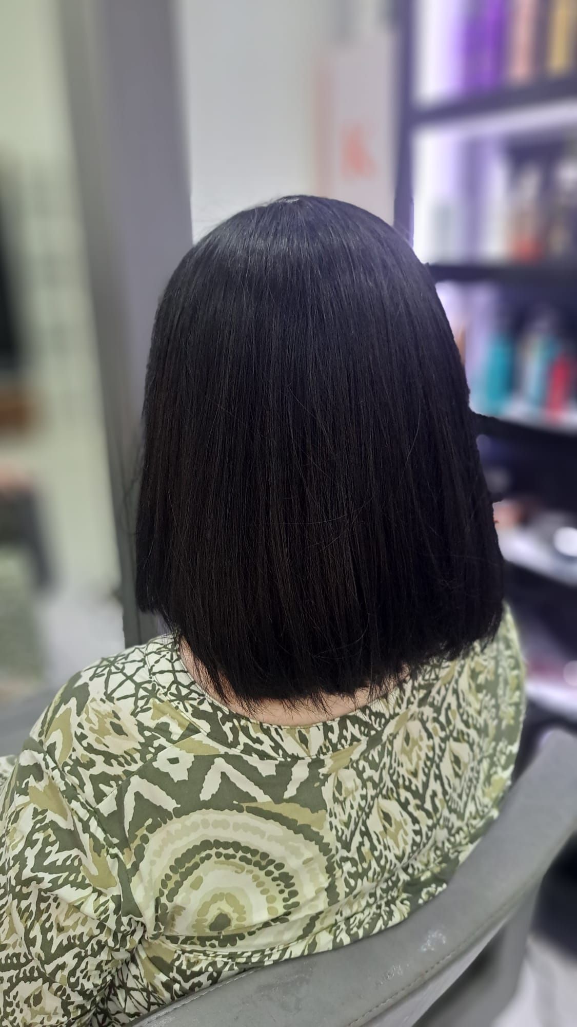 Una mujer con cabello corto y negro está sentada en una silla en un salón.