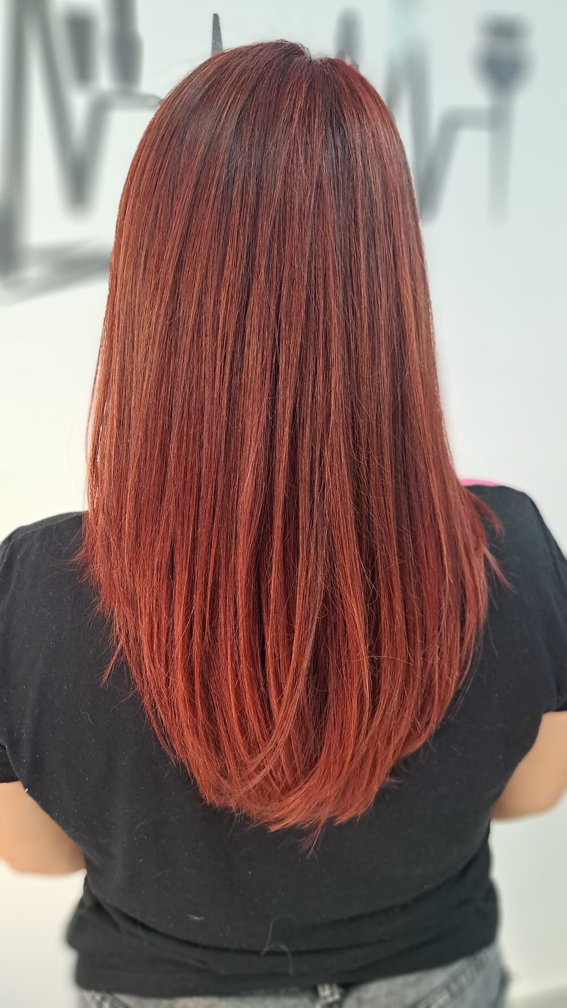Una mujer con cabello largo y rojo lleva una camisa negra.