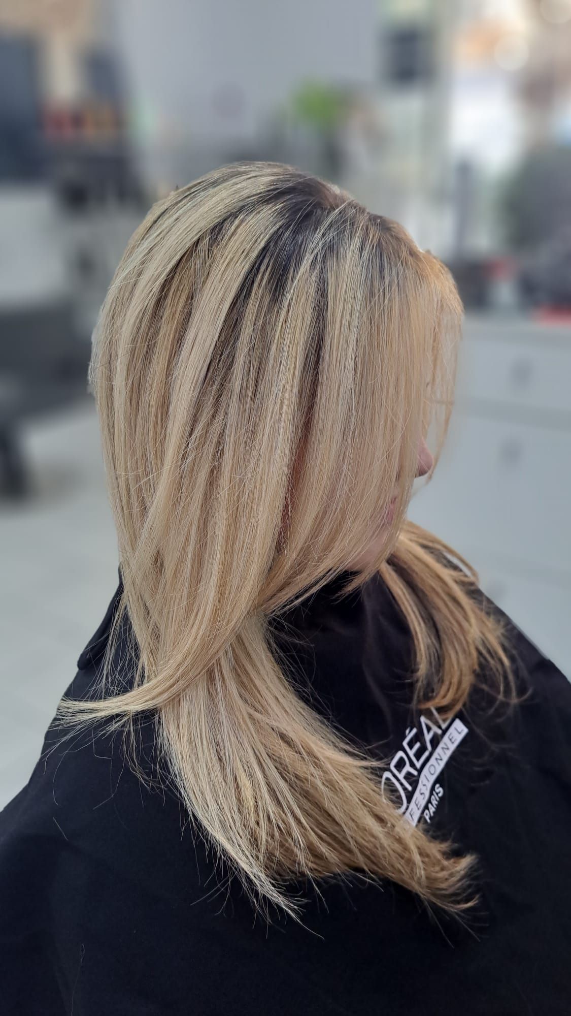 Una mujer con cabello rubio lleva una capa negra en un salón.