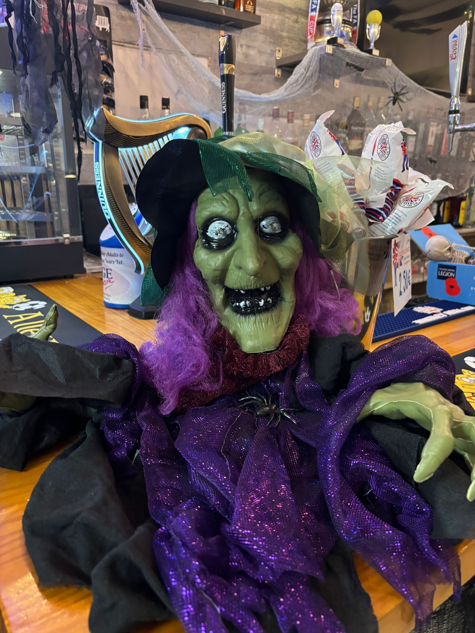 Una muñeca bruja está sentada en una mesa de madera.