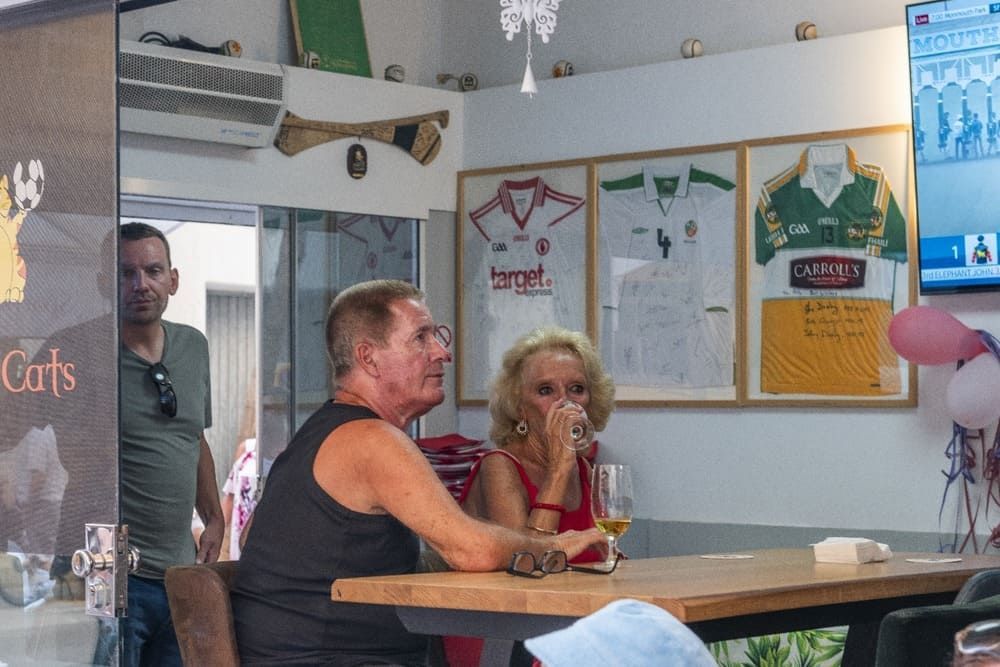 Un hombre y una mujer están sentados en una mesa bebiendo vino.