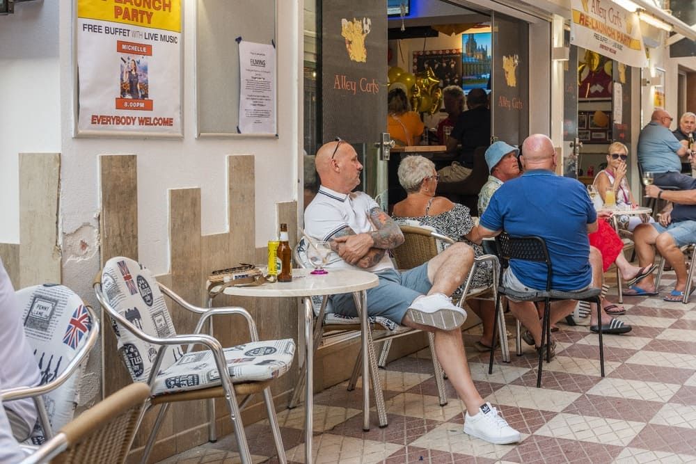 Un grupo de personas están sentadas en mesas afuera de un restaurante.