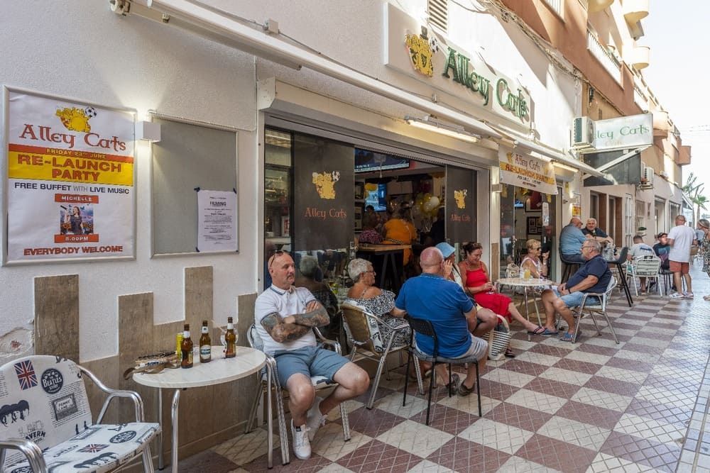 Un grupo de personas están sentadas en mesas afuera de un restaurante.