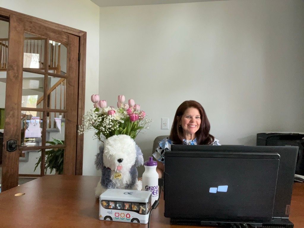 A woman is sitting at a desk in front of a laptop computer.