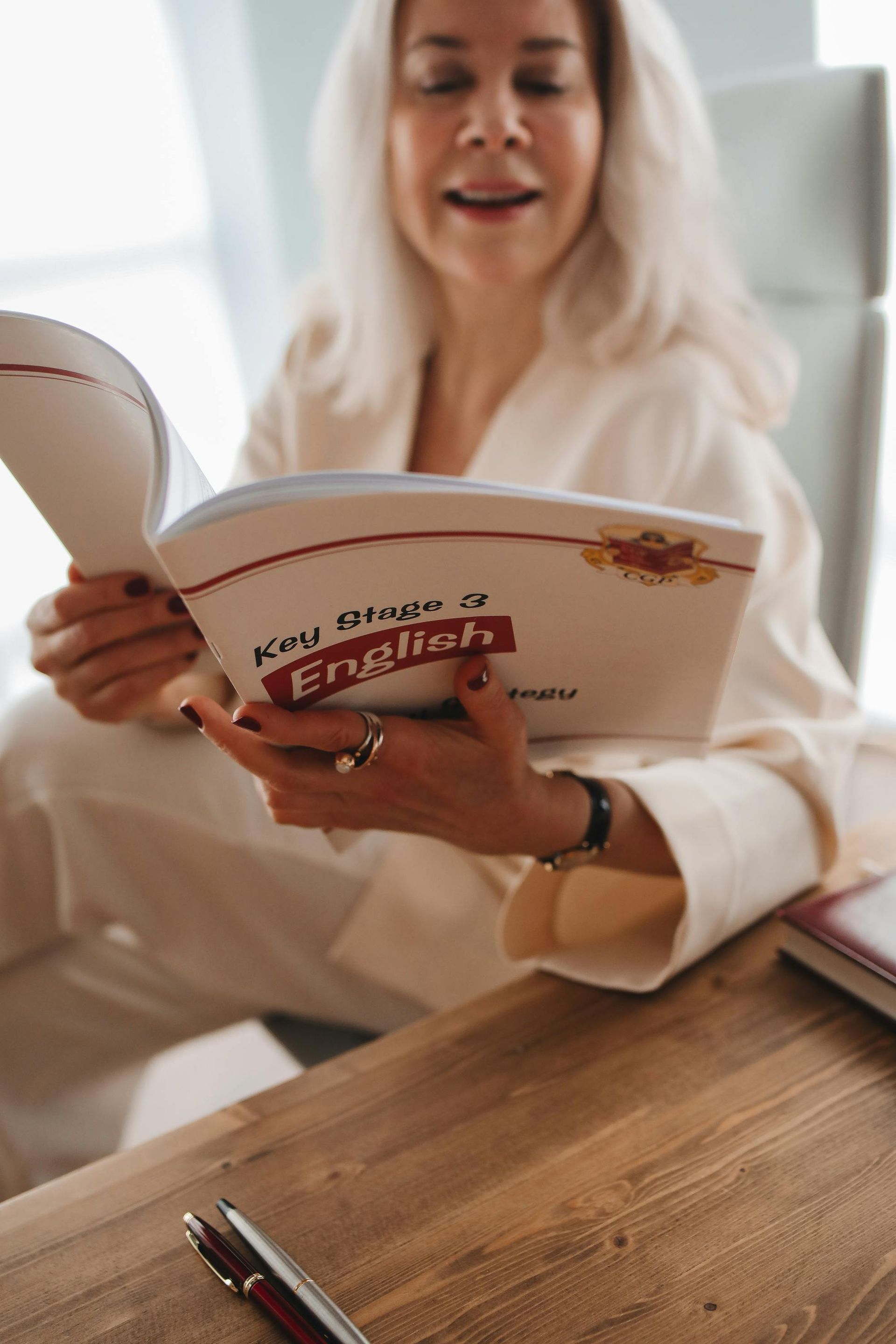 A woman is sitting at a table reading a book.