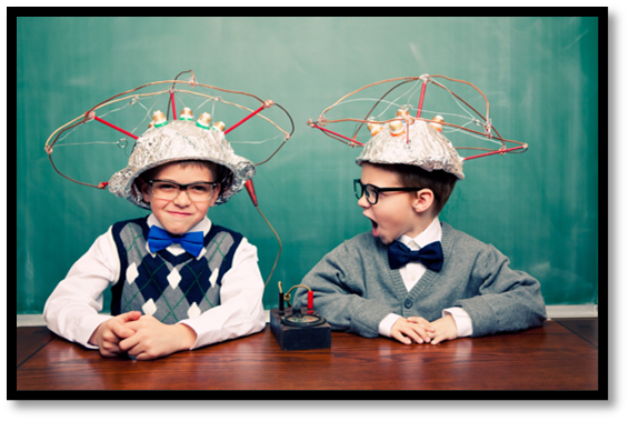 Two boys are sitting at a table with hats on their heads.