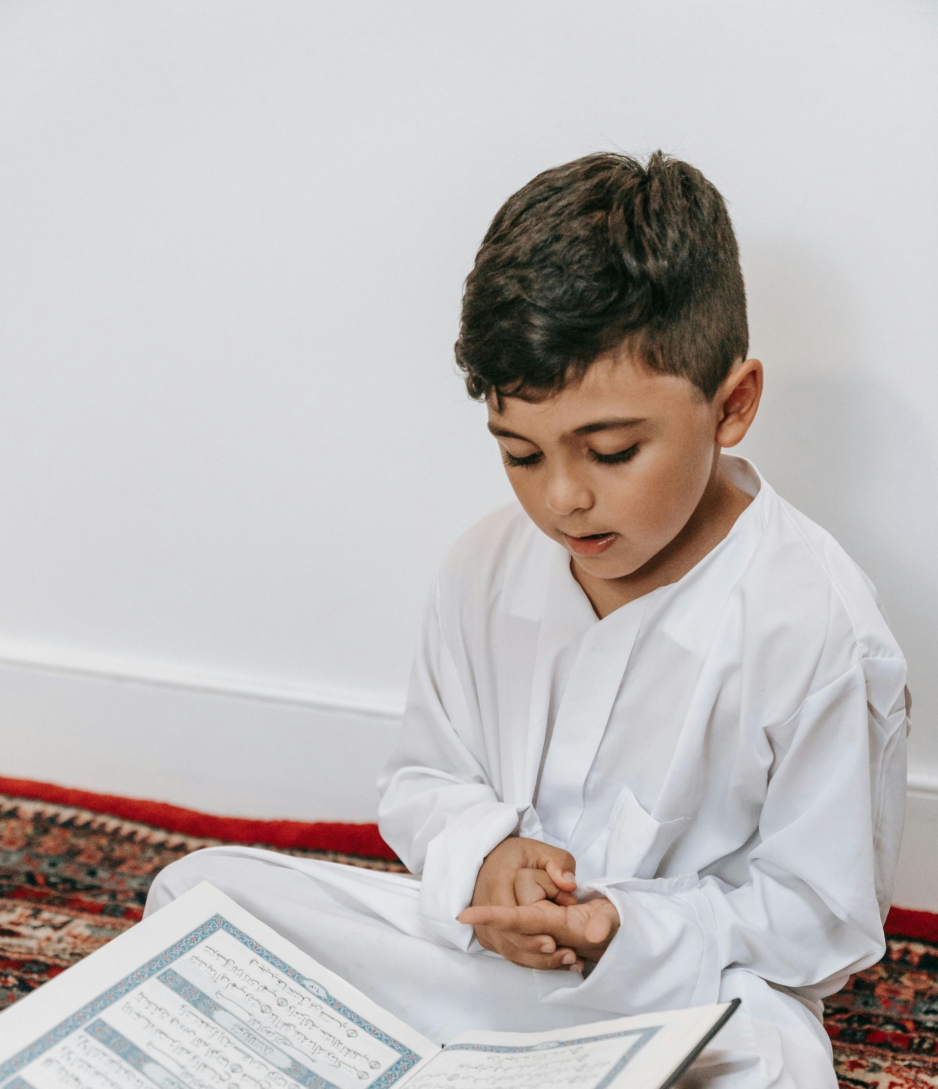 A young boy is sitting on the floor reading a book.