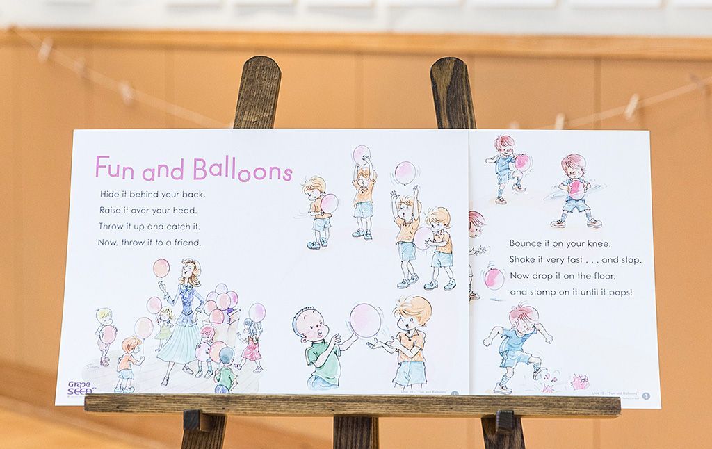 A book titled fun and balloons is sitting on a wooden easel.