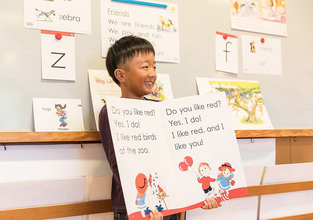 A young boy is holding a sign in a classroom.