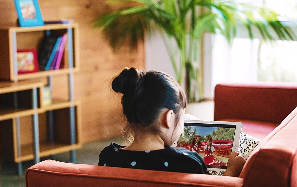 A woman is sitting on a couch using a tablet computer.