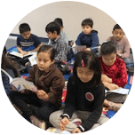 A group of children are sitting on the floor reading books.