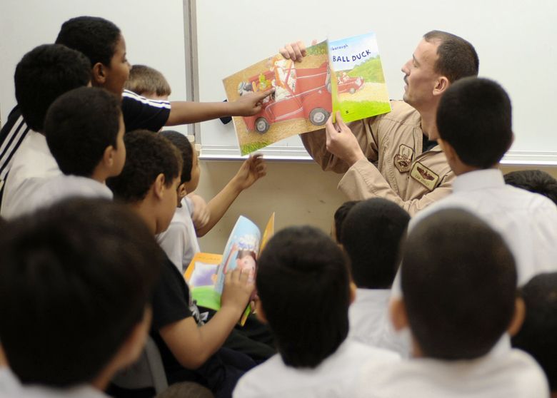 A man is reading a book to a group of children