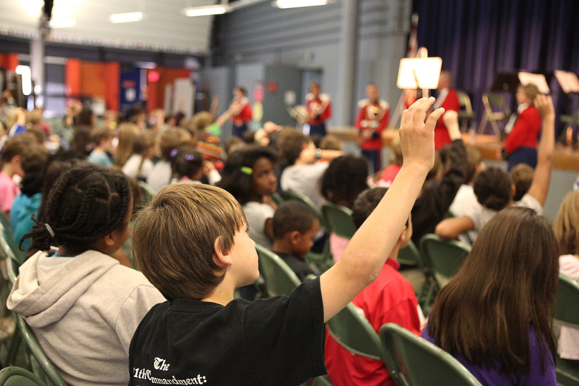 A boy is raising his hand in a crowd of children