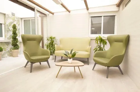 Una sala de estar con sillas verdes, un sofá y una mesa de café.