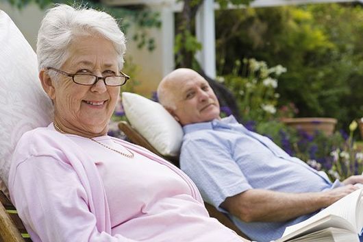 Una pareja de ancianos está sentada en sillas de jardín.