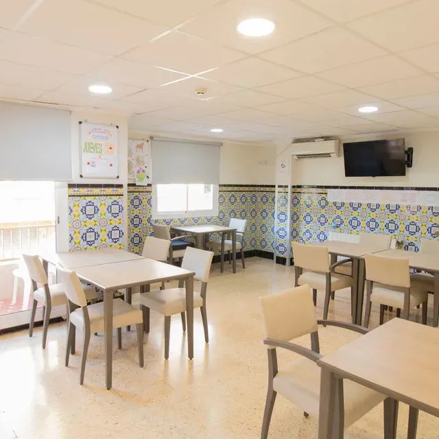 Un comedor con mesas y sillas y un televisor en la pared.