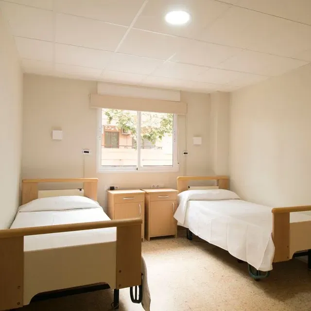 Una habitación de hospital con dos camas y una ventana.