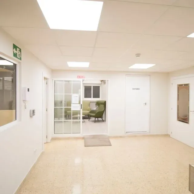 Un pasillo con una señal de salida verde en la pared.