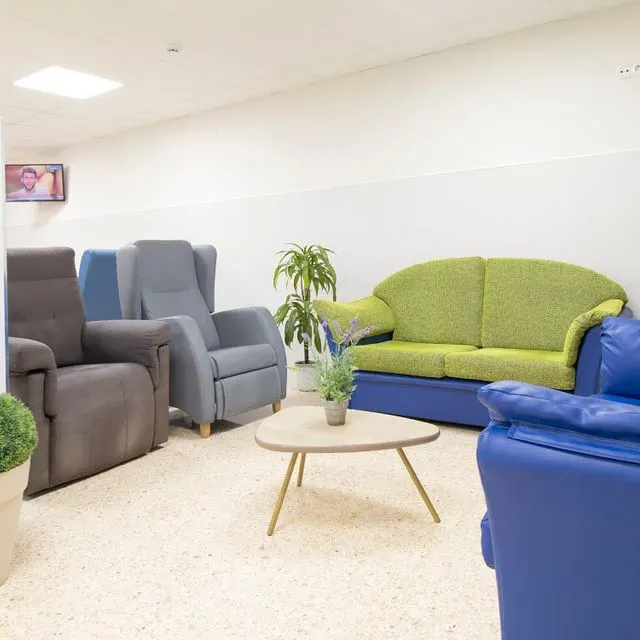 Una sala de estar con sillas azules y un sofá verde.