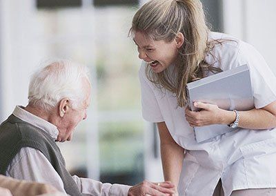 Una enfermera está hablando con un anciano en silla de ruedas.