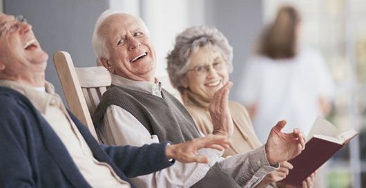 Un grupo de personas mayores están sentadas en mecedoras riendo.