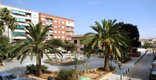 Un parque con palmeras y un edificio al fondo.