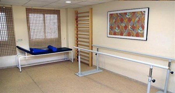 Una habitación con una cama, rejas y un cuadro en la pared.