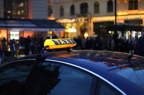 Taxi abends in der Innenstadt zwischen vielen Menschen