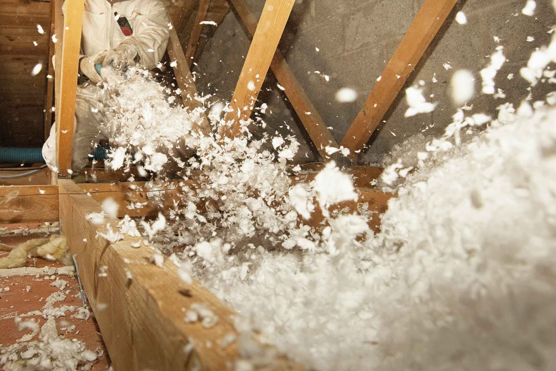 Un couvreur soufflant de l'isolation dans des combles