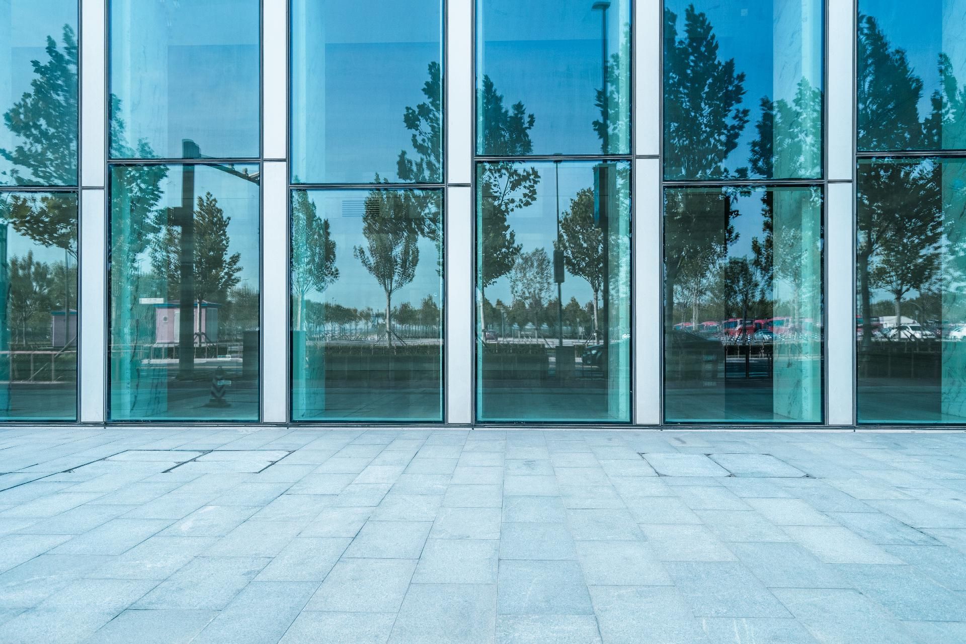 Moderne Glasfassade mit reflektierenden Fenstern und einem leichten Steinweg