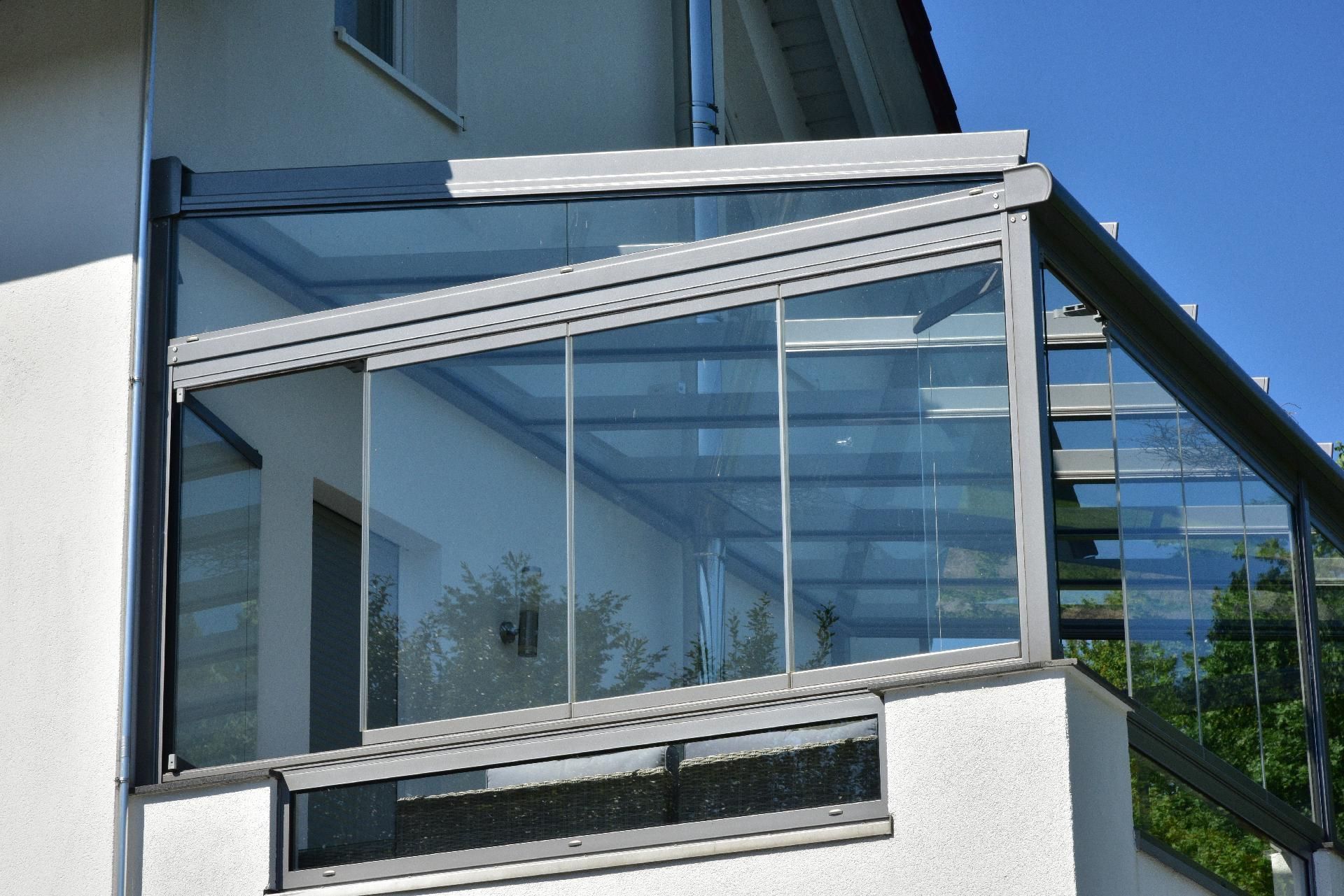 Verglaster Balkon mit weißem Geländer an einem modernen Gebäude unter blauem Himmel