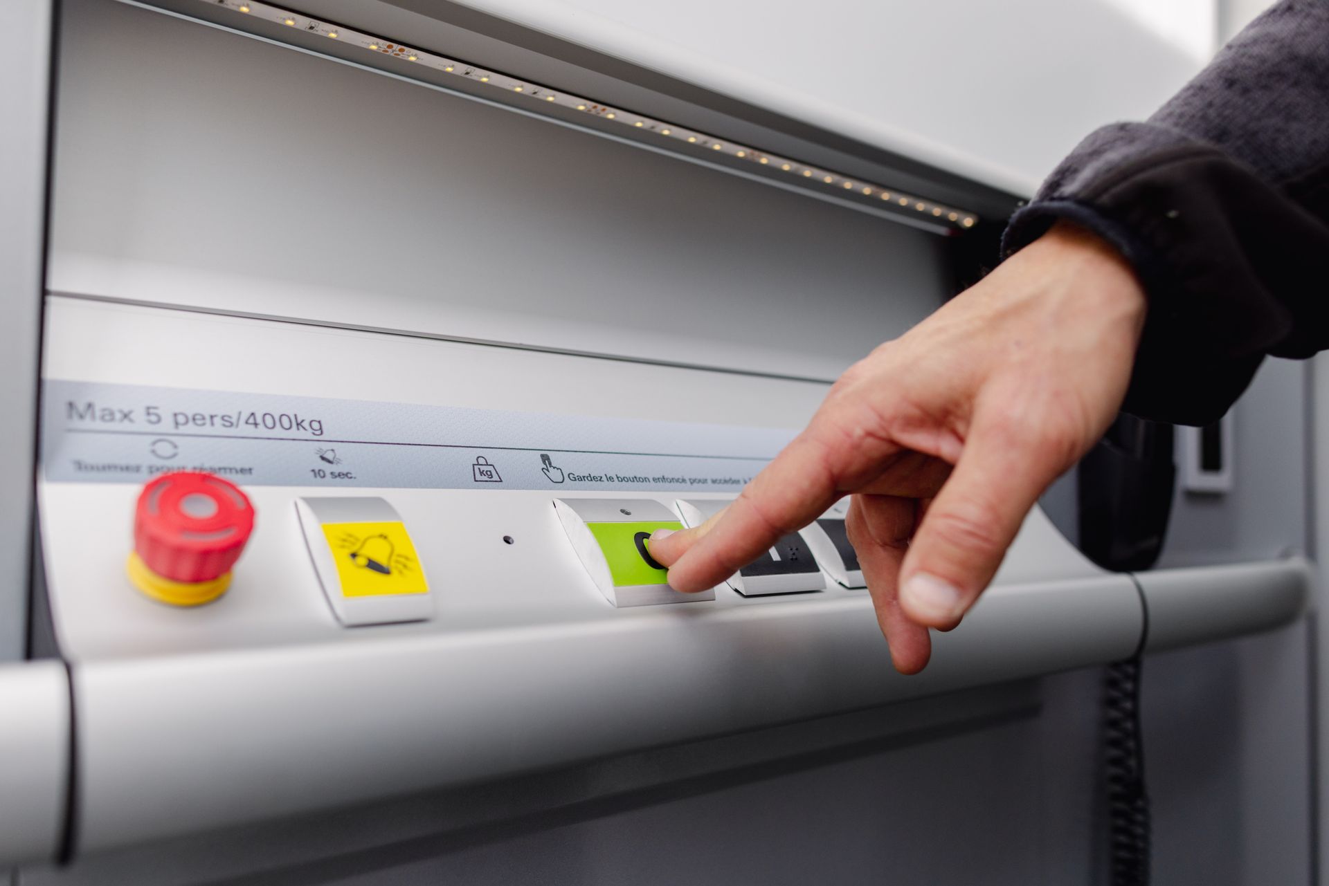 Un homme appuyant sur une touche verte dans un ascenseur