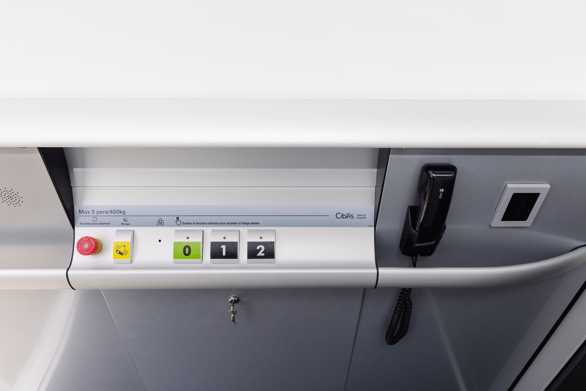 Panneau de commande dans un train. Boutons : rouge, jaune, vert, 0, 1, 2. Téléphone, panneau blanc et serrure.