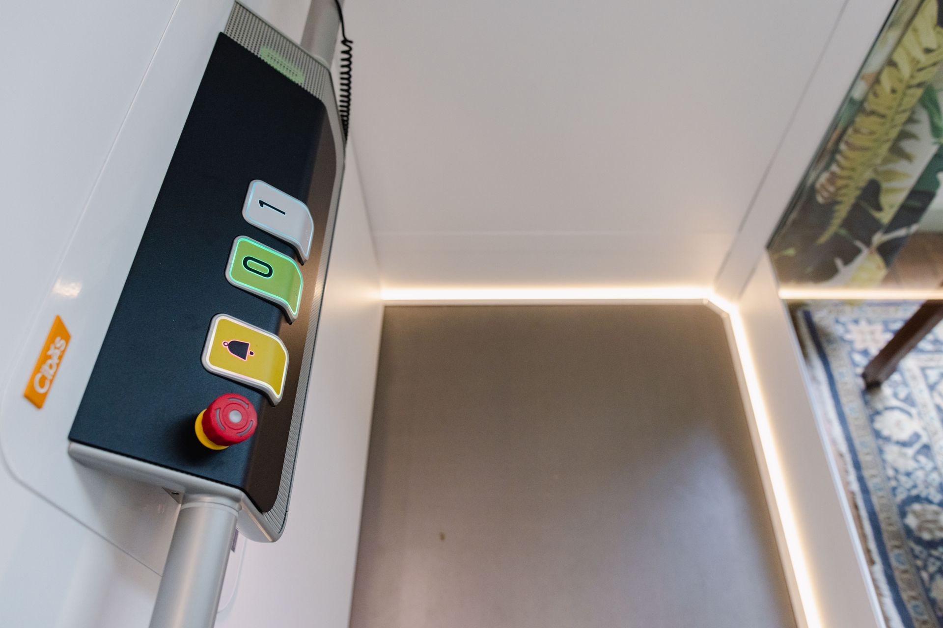 Panneau de commande avec boutons sur un mur blanc ; bouton d’arrêt rouge, boutons vert, jaune et blanc.