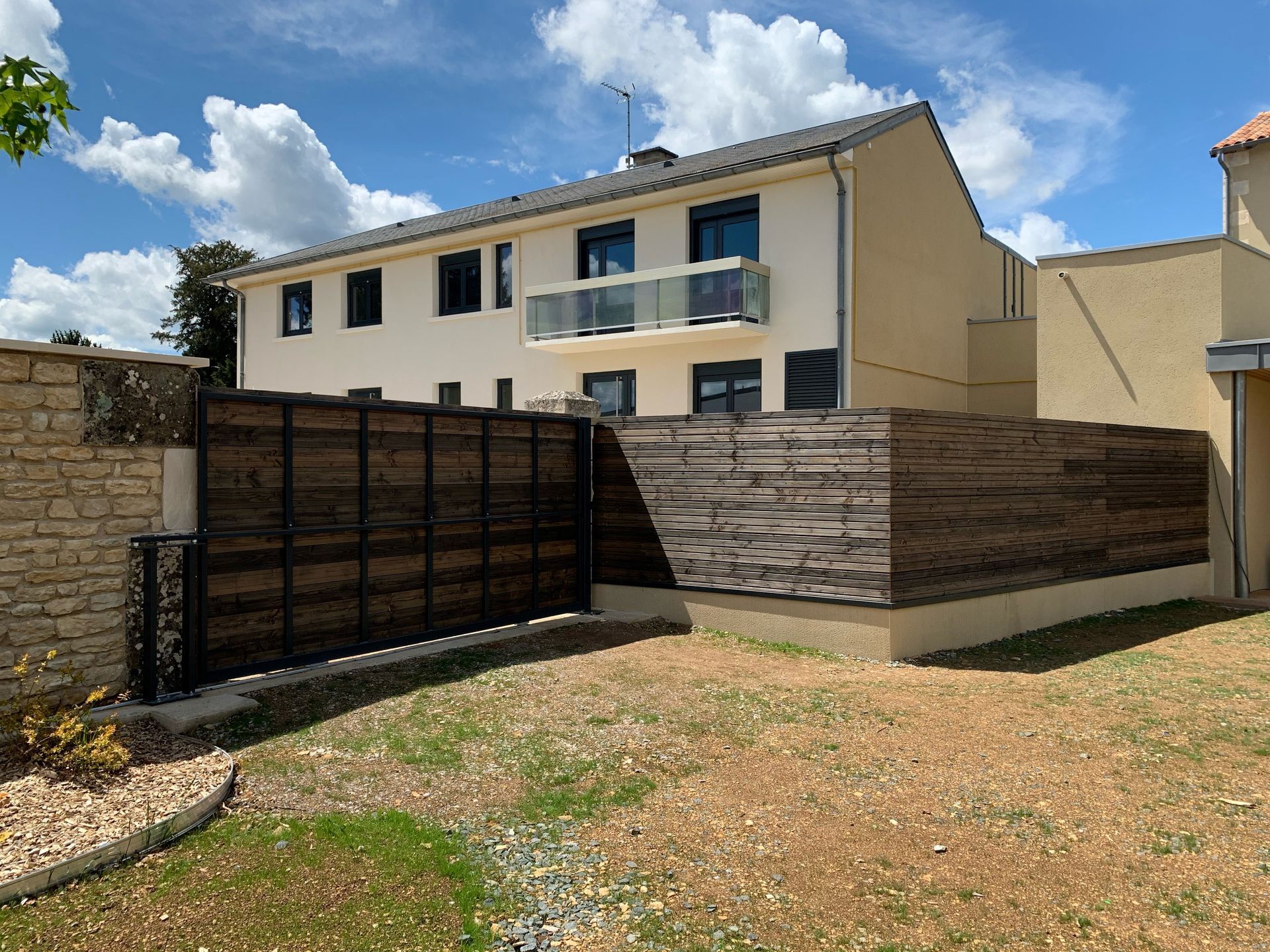 Portail et barrière en bois devant maison blanche
