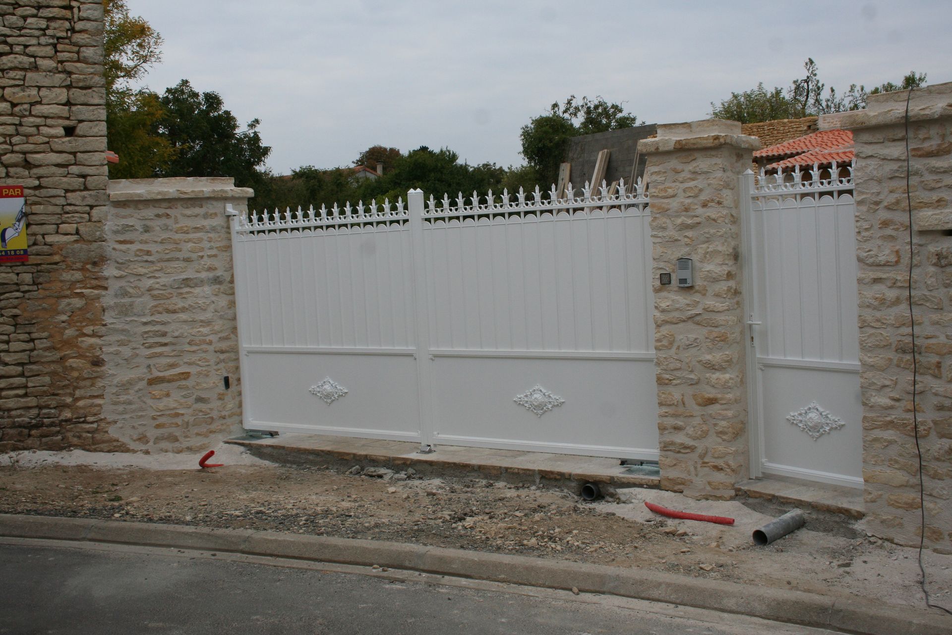 Portail blanc avec ornements et poteaux à pierres apparentes