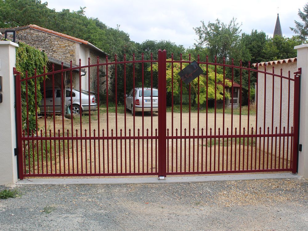 Portail en fer forgé donnant sur une propriété avec deux voitures