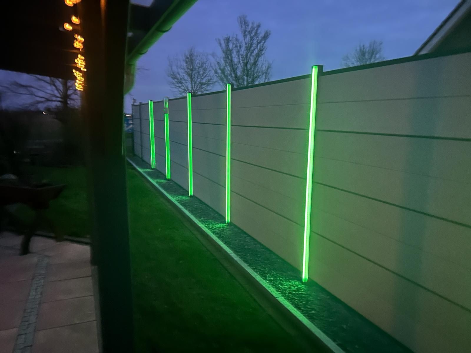 Ein Zaun mit grünen Lichtern ist nachts beleuchtet.