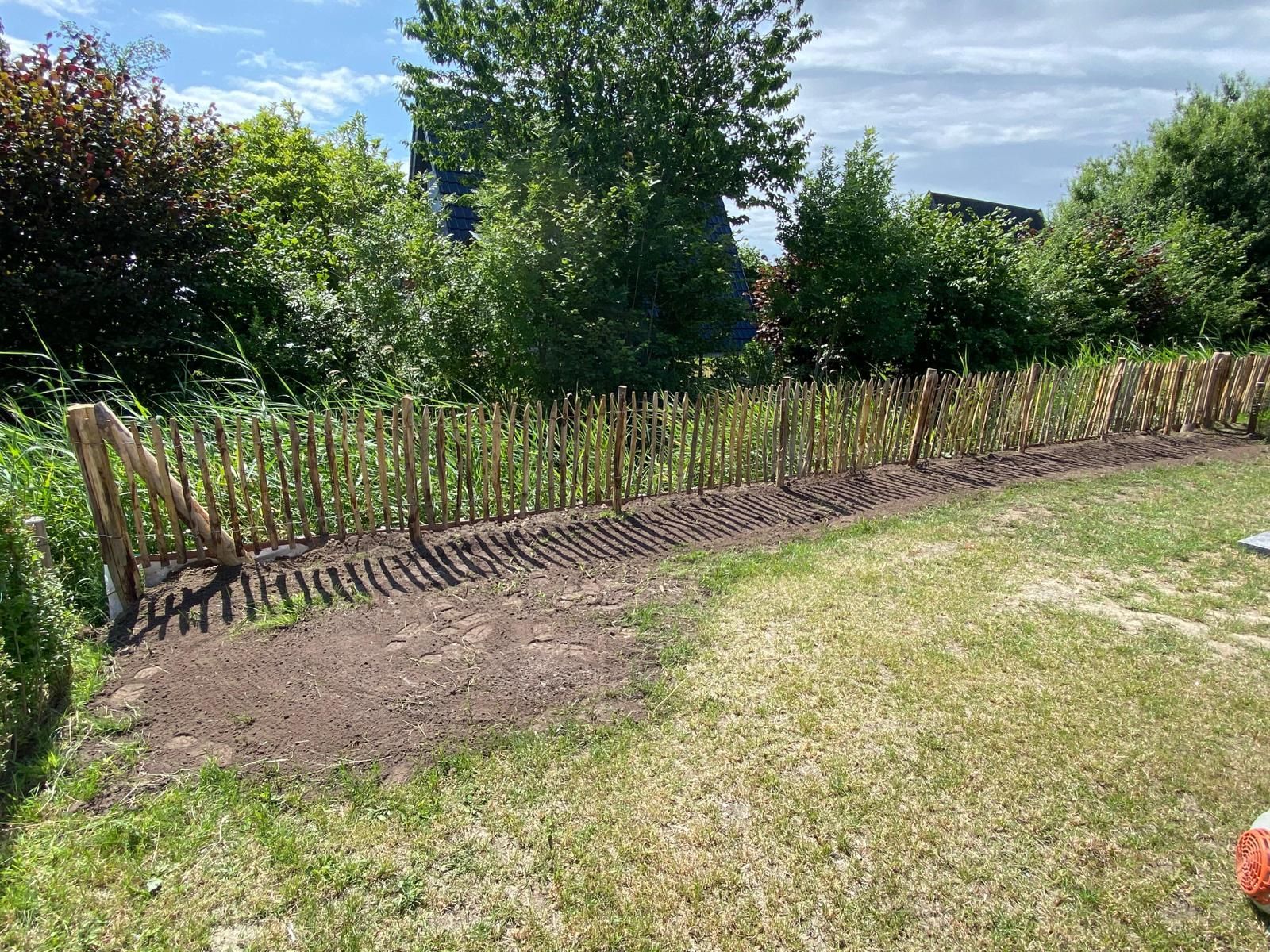 Ein Holzzaun umgibt eine Wiese in einem Hinterhof.