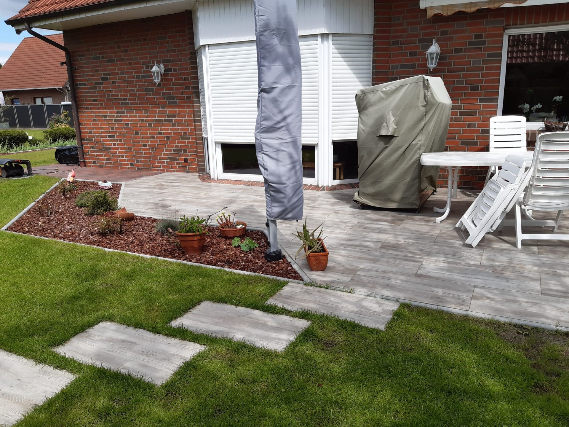 Eine Terrasse mit Tisch und Stühlen vor einem Backsteinhaus.