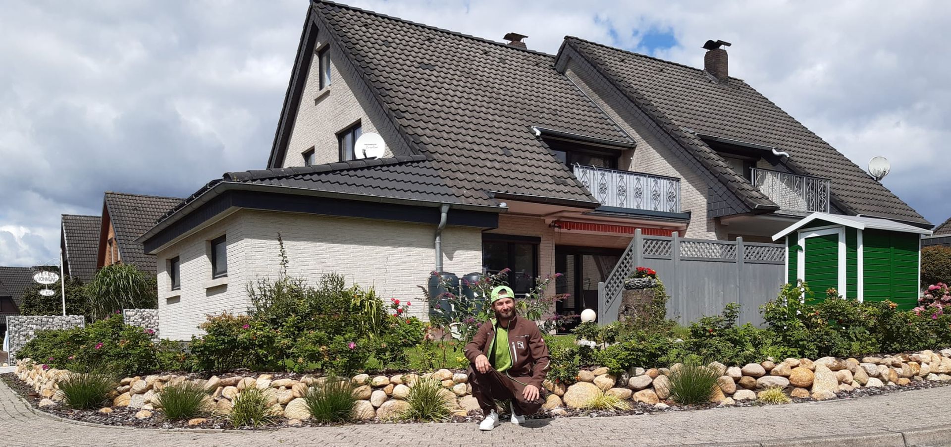 Ein Mann kniet vor einem großen Haus.