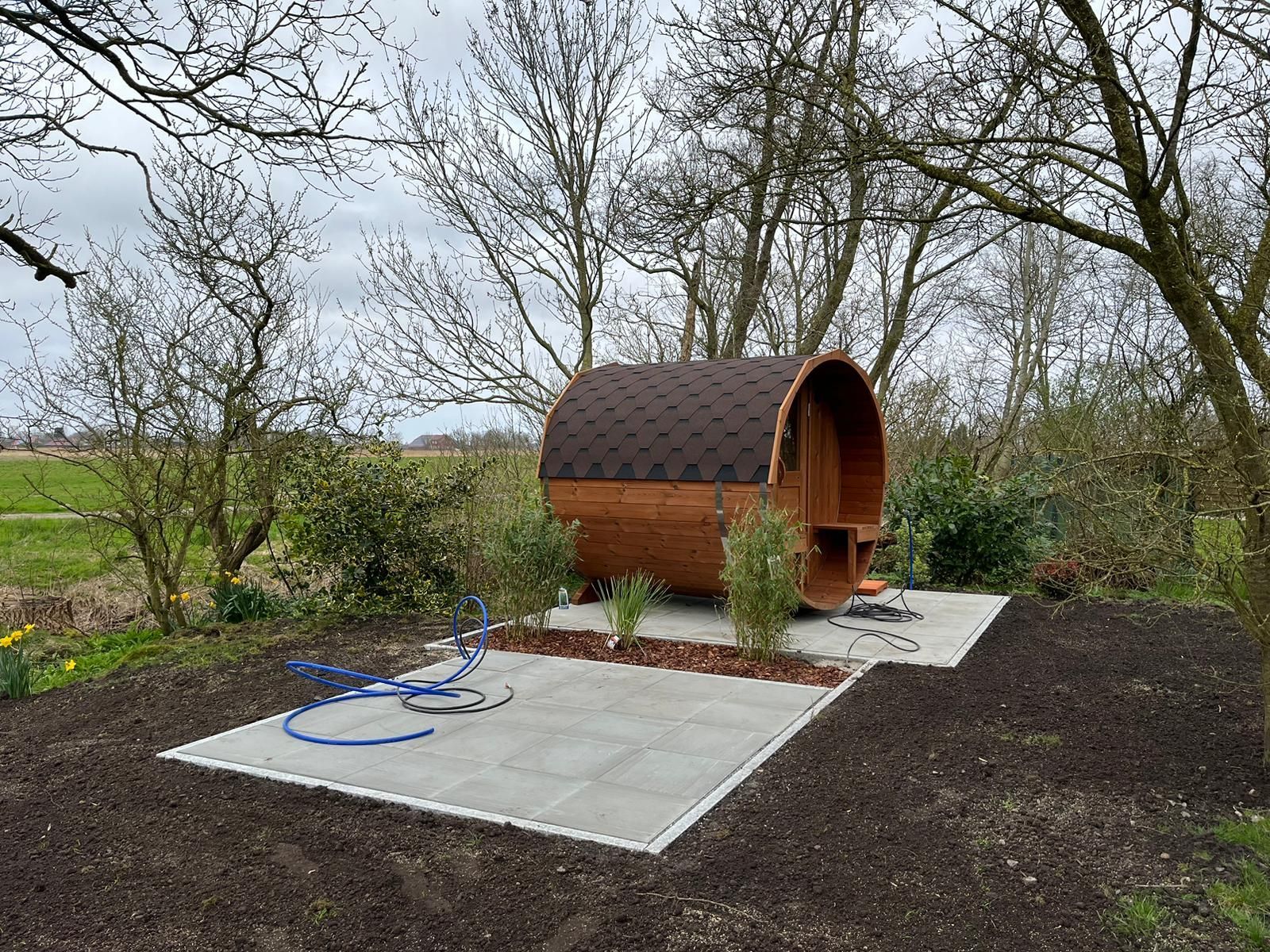 Ein Holzfass steht auf einer Betonterrasse mitten auf einem Feld.