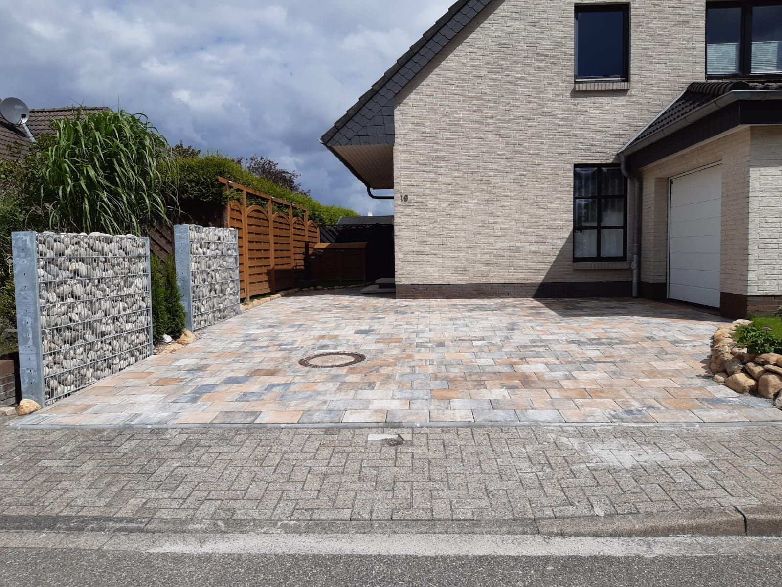 Ein Backsteinhaus mit einer Backsteinauffahrt davor.