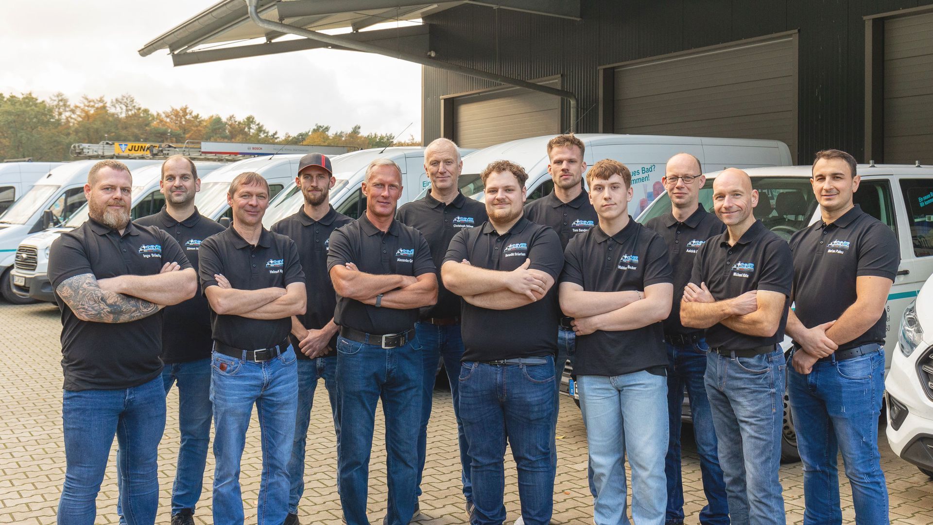 Eine Gruppe von Männern steht vor einer Reihe von Lieferwagen.