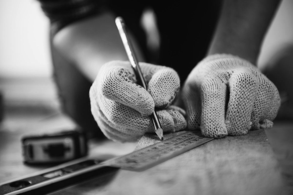 Eine Person mit Handschuhen schreibt mit einem Stift auf ein Blatt Papier.