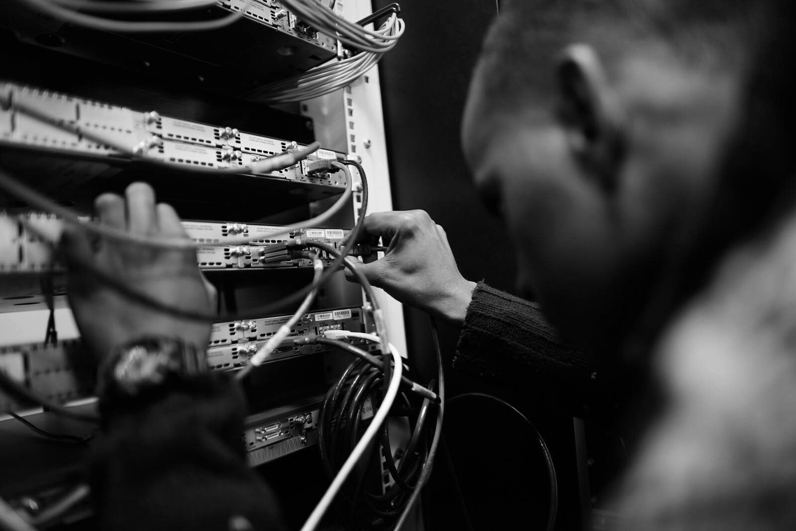 Auf einem Schwarzweißfoto arbeitet ein Mann an einem Server.